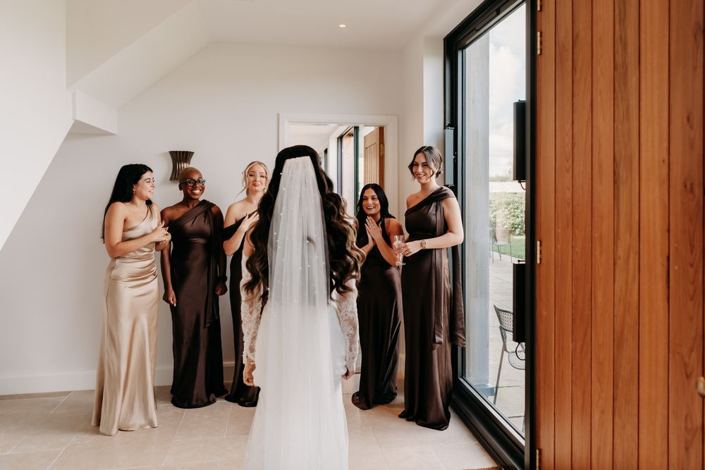 A series of elegant wedding party photos showing bridesmaids in black and blush dresses getting ready in a bright room.