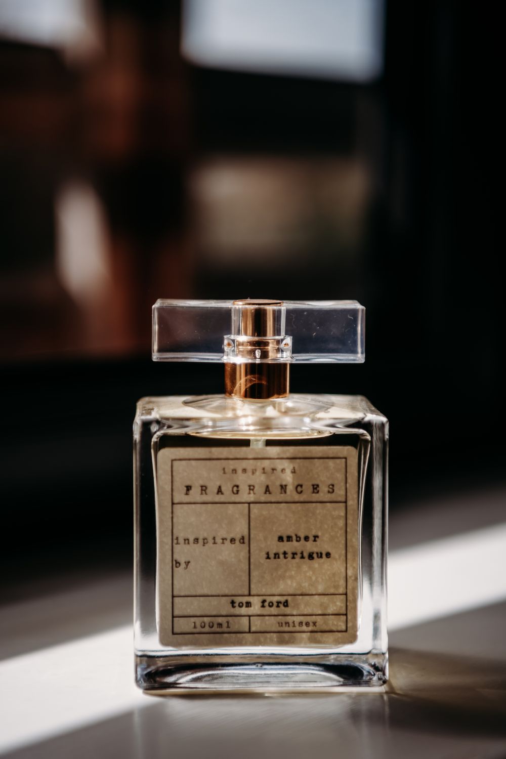 Glass perfume bottles with minimalist labels displayed in natural lighting on reflective surface.