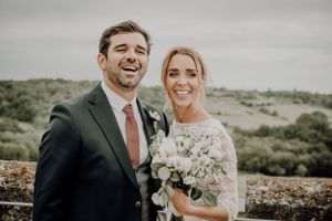Wedding couple sharing a joyful moment together on stone wall with countryside views. photographe mariage Bordeaux gironde