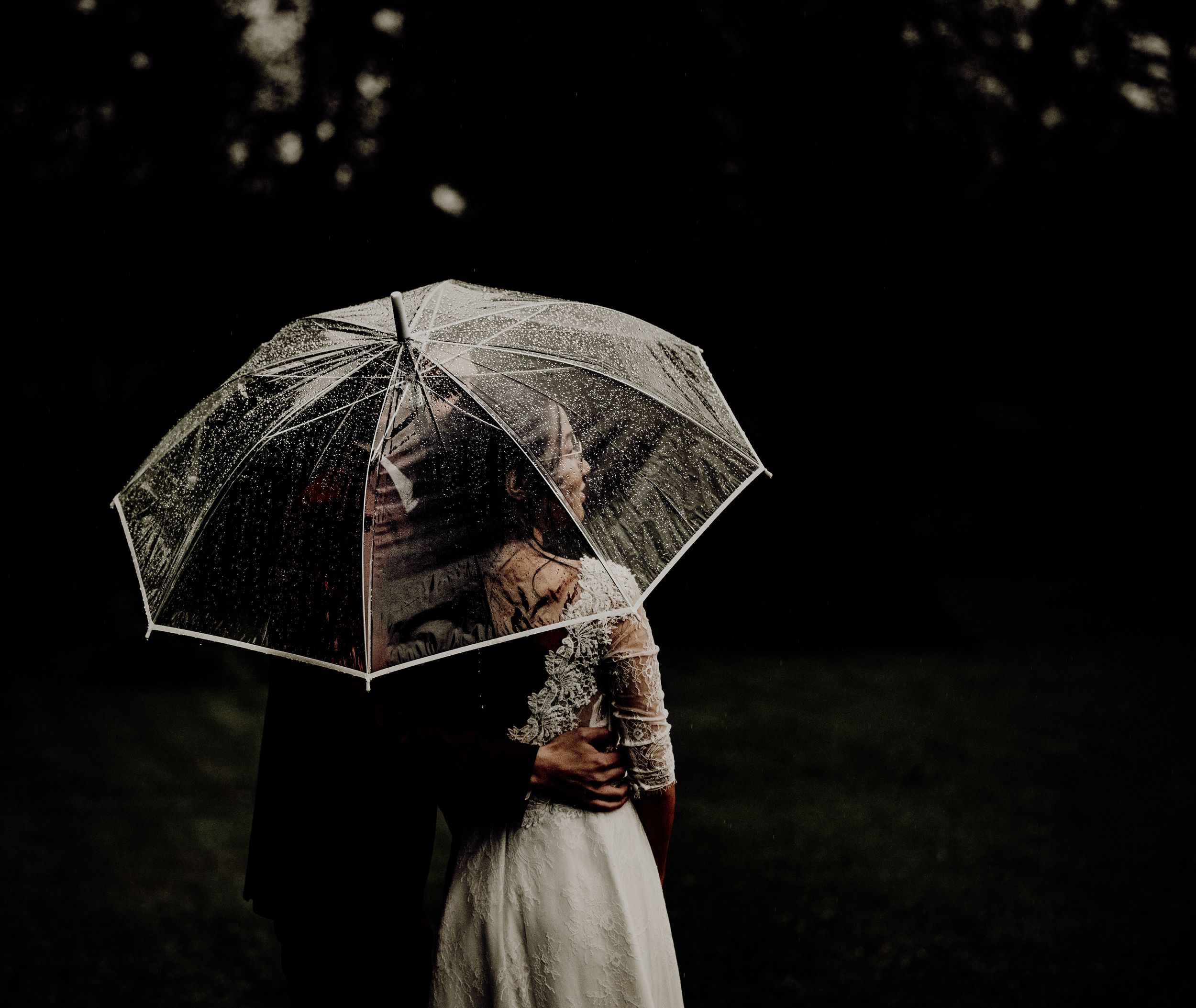 A couple shares an intimate moment under a clear umbrella during their wedding photoshoot. photographe mariage Bordeaux, Gironde