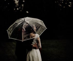 A couple shares an intimate moment under a clear umbrella during their wedding photoshoot. photographe mariage Bordeaux, Gironde