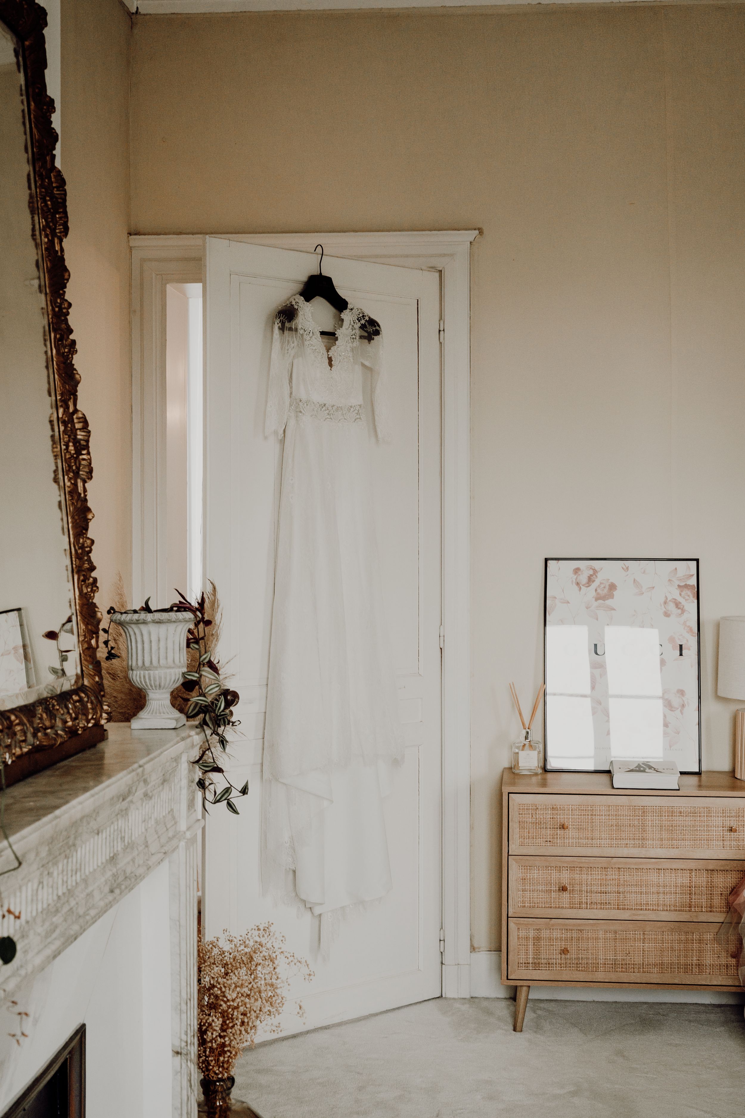 White wedding dress hanging on door in minimalist room with vintage furniture. photographe mariage Bordeaux, Gironde