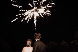 Newlyweds share their first dance surrounded by sparklers held by wedding guests in a nighttime celebration.