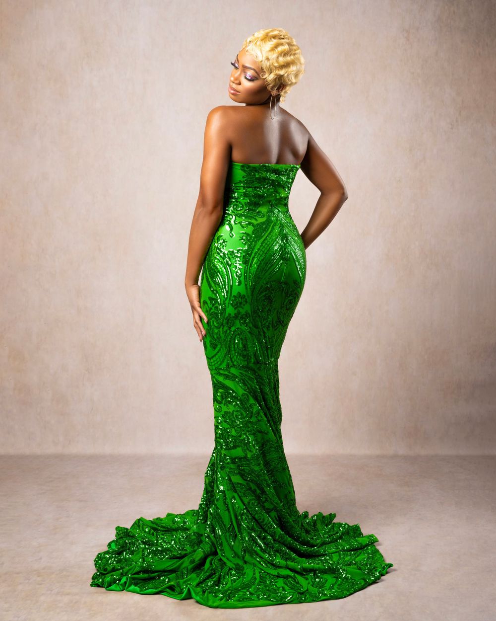 Back view of an emerald green sequined evening gown with flowing train.