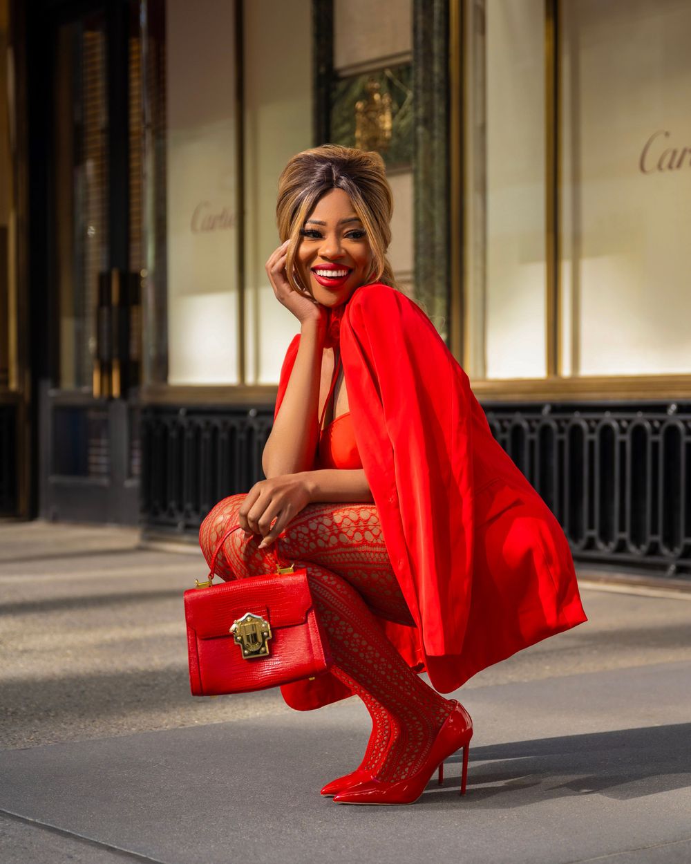 Red monochromatic fashion look with matching handbag captured in front of Cartier boutique.