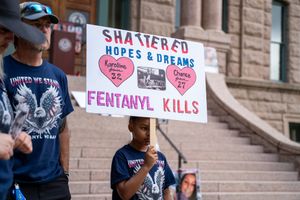 Protester holding sign about fentanyl awareness at public demonstration.