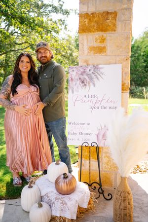 Fall-themed baby shower decor with pink accents, pumpkins and welcome signs.