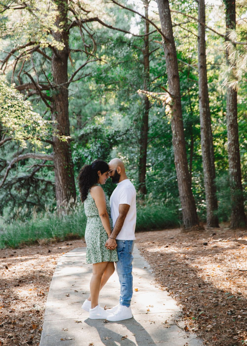 Couple stands close together on a wooded path during a romantic photoshoot.