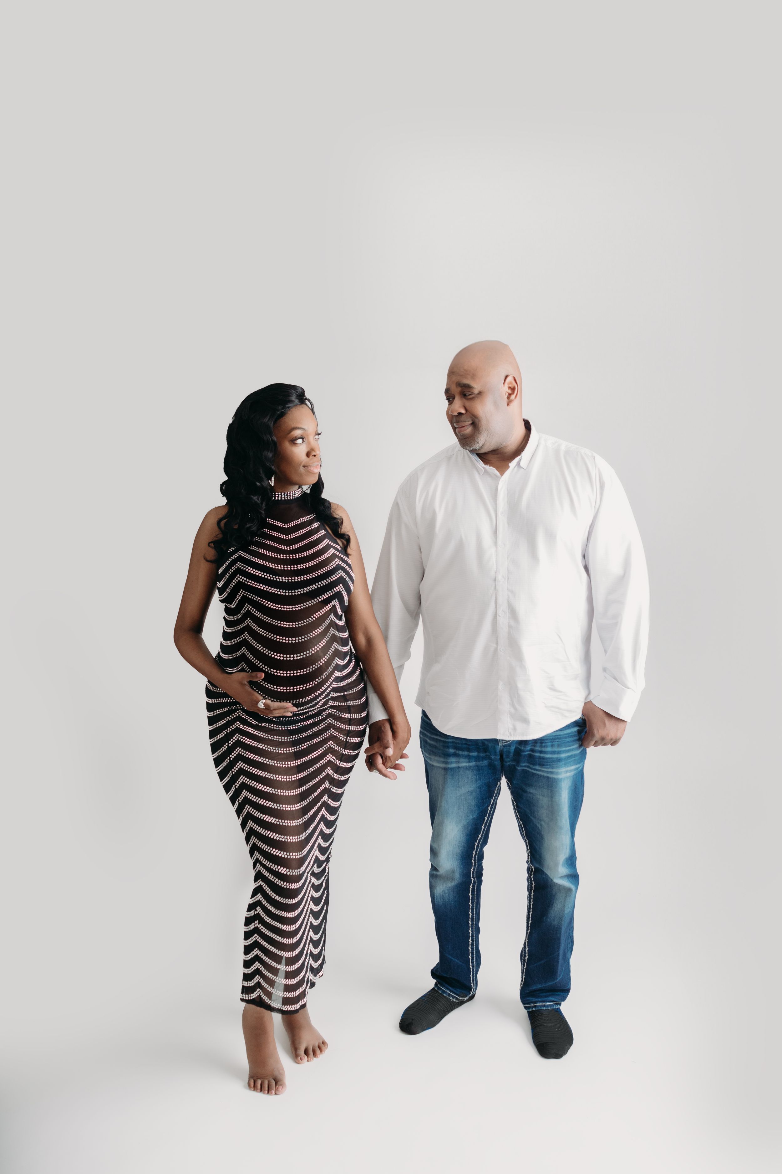 A maternity couple stands together on a white background during maternity photos in Tampa