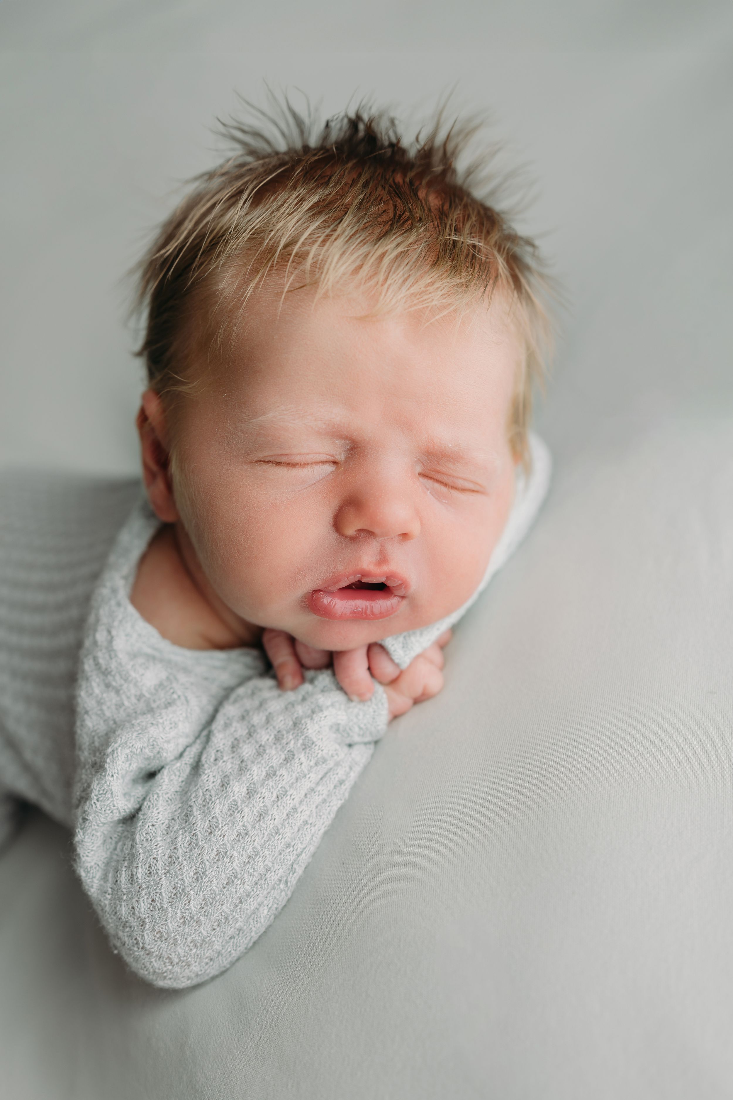 Close-up of a sleeping newborn baby boy in green during best newborn photographer in Tampa session