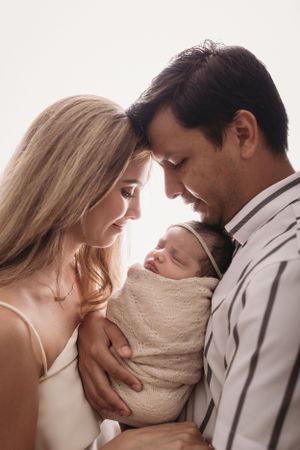 Sweet intimate moment between couple embracing in neutral tones with newborn baby girl during newborn photos in Tampa, Florida