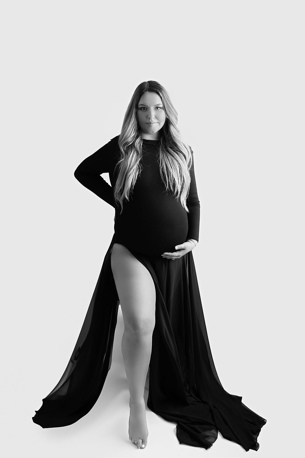 Black and white artistic maternity portrait showing a dramatic flowing dress against white background for Maternity Photography in Tampa