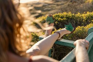 Green floral sandals shown in sunlit garden with yellow flowers.