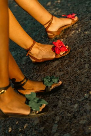 Close-up of feet wearing decorative sandals with red and green floral embellishments.