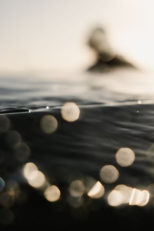 Abstract bokeh lights reflecting on ocean water surface at sunset.