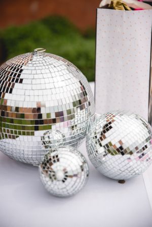 Three mirrored disco balls of varying sizes displayed on white surface with polka dot decor.