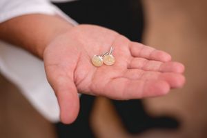 Small gold stud earrings displayed in open palm.
