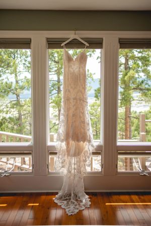 Lace wedding dress hanging in window with mountain view and natural light.