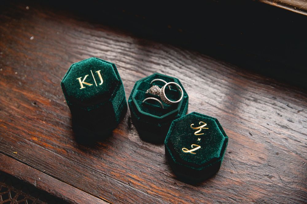 A collection of antique style emerald green velvet ring boxes displayed on a dark wooden surface.