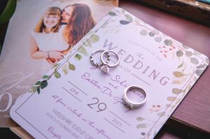Wedding invitation cards laid out on a pink surface with floral designs and elegant calligraphy.