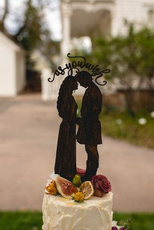 Wedding cake topper silhouette against blurred garden background.