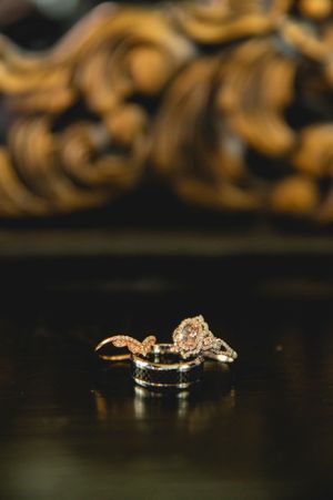 Close-up of elegant wedding rings with vintage-style diamond settings on dark surface.