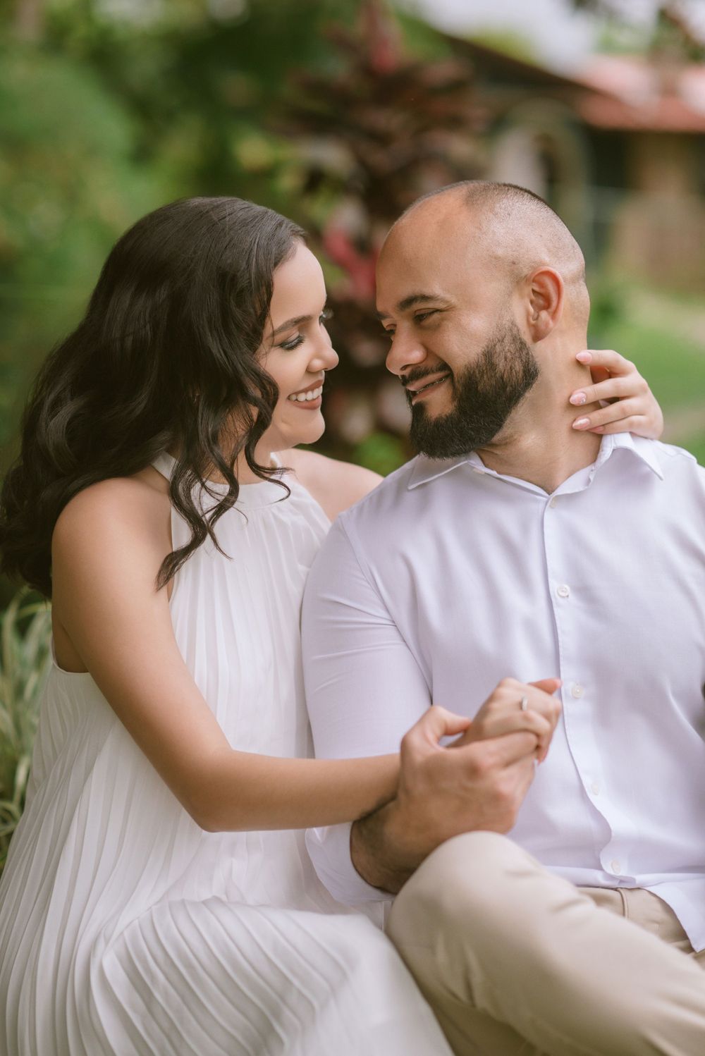 Couple in white outfits share tender moment outdoors while dancing together.