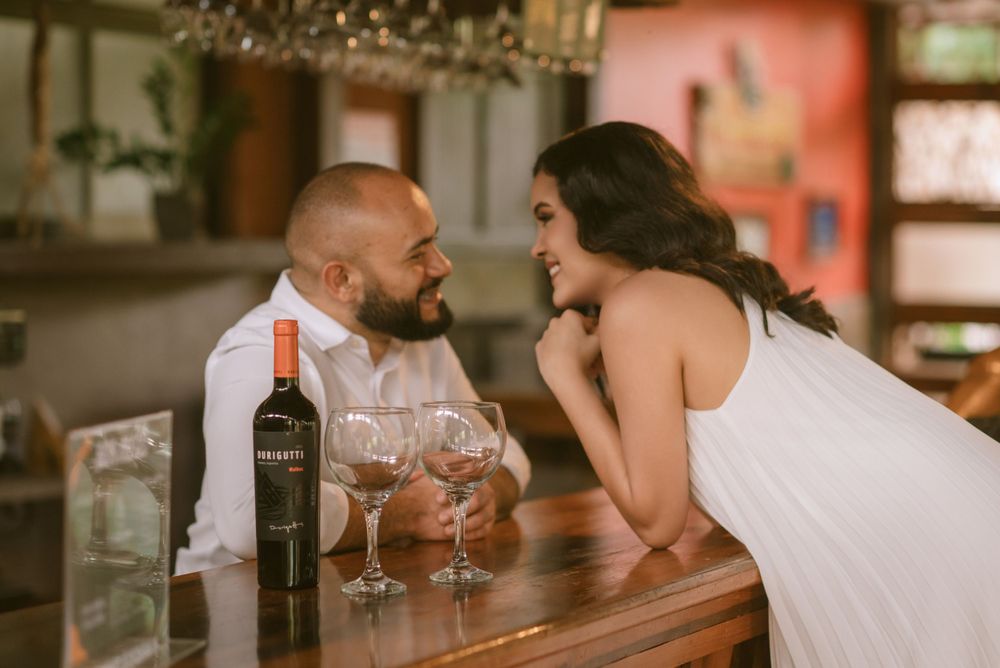 Romantic wine bar engagement photo with couple sharing intimate moment over glasses of red wine.