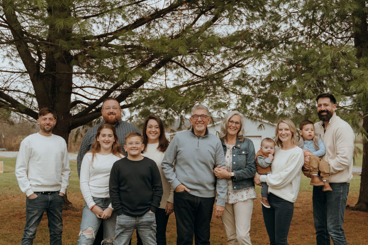 Large Family Smile for a beautiful photo. Grandparents are surrounded by their children and grandchildren. Coordinated outfits, denim, white