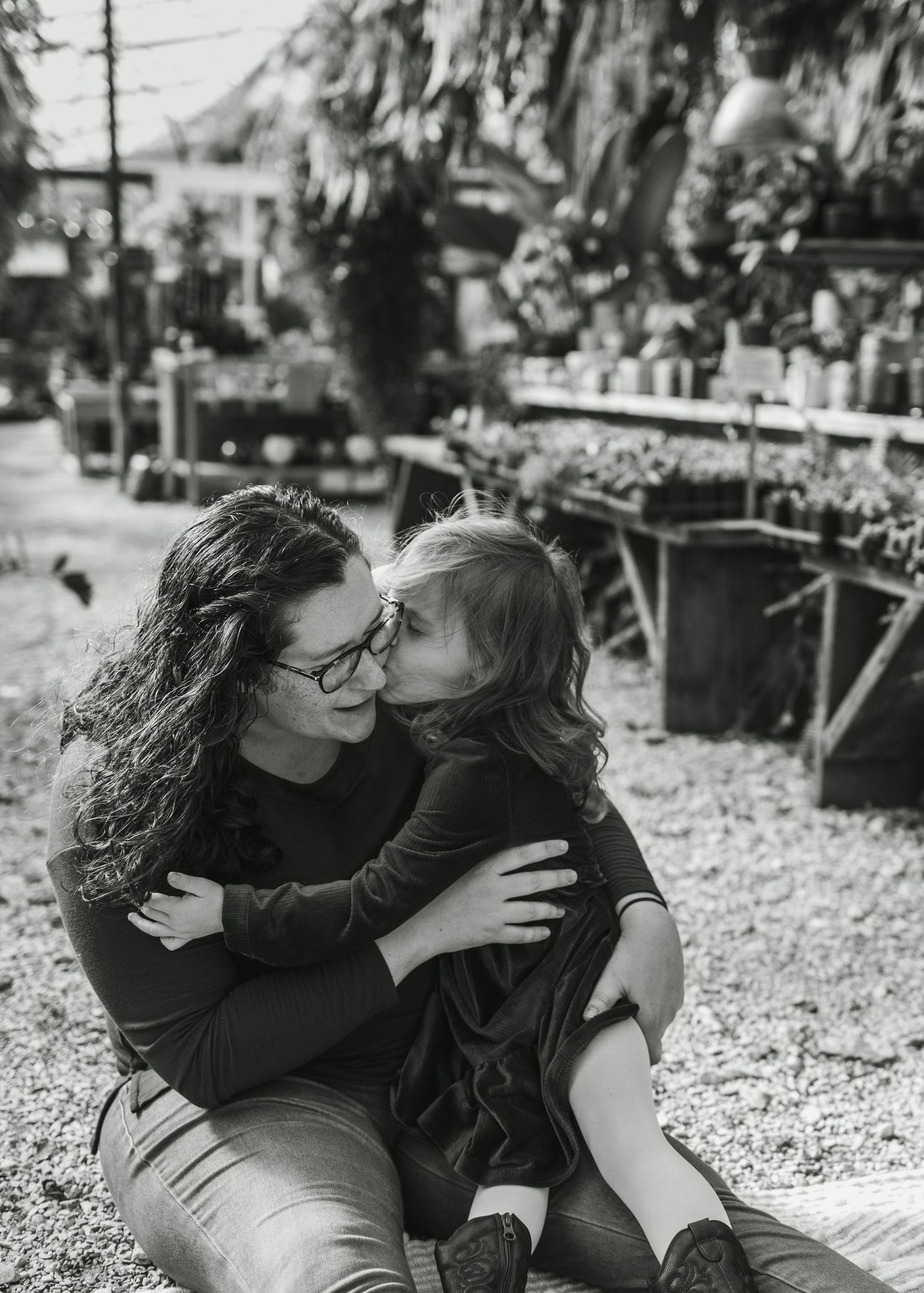 Family sharing joyful moment together in greenhouse filled with plants.