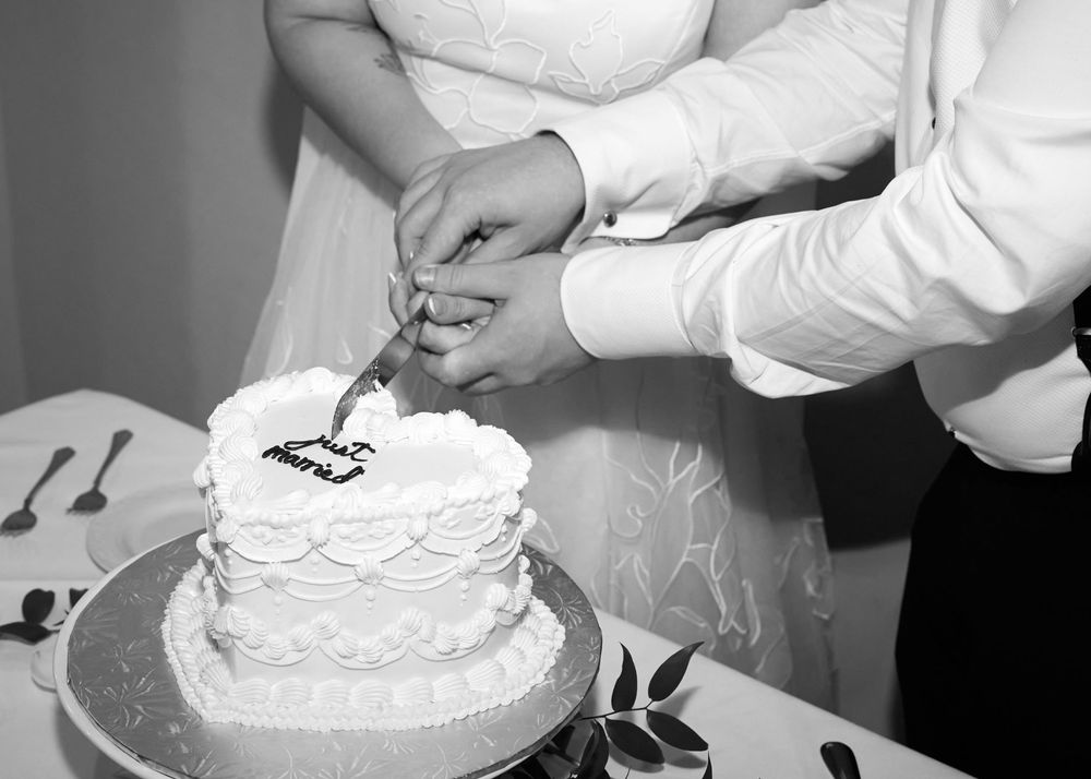A series of hands decorating a white frosted cake with piping techniques and adding final touches to the dessert.