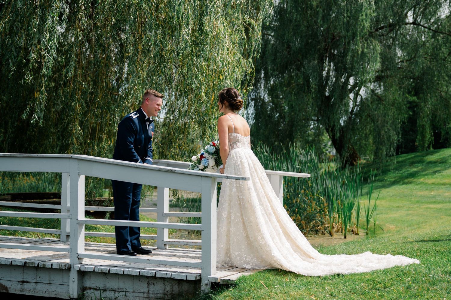 Elegant outdoor wedding ceremony setup with white chairs and willow trees in the background.