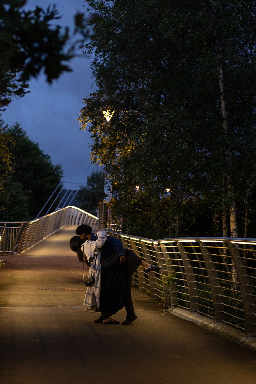cinematic storytelling photo of a couple dancing on the bridge in late afternoon under the light of street lamps in Galway, Ireland