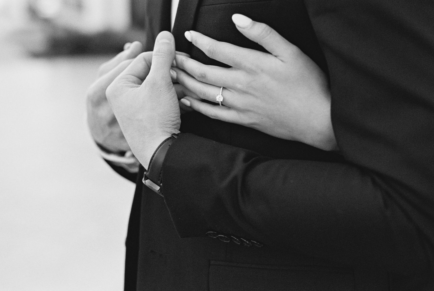 Black and white close-up of hands with wedding rings during ceremony.