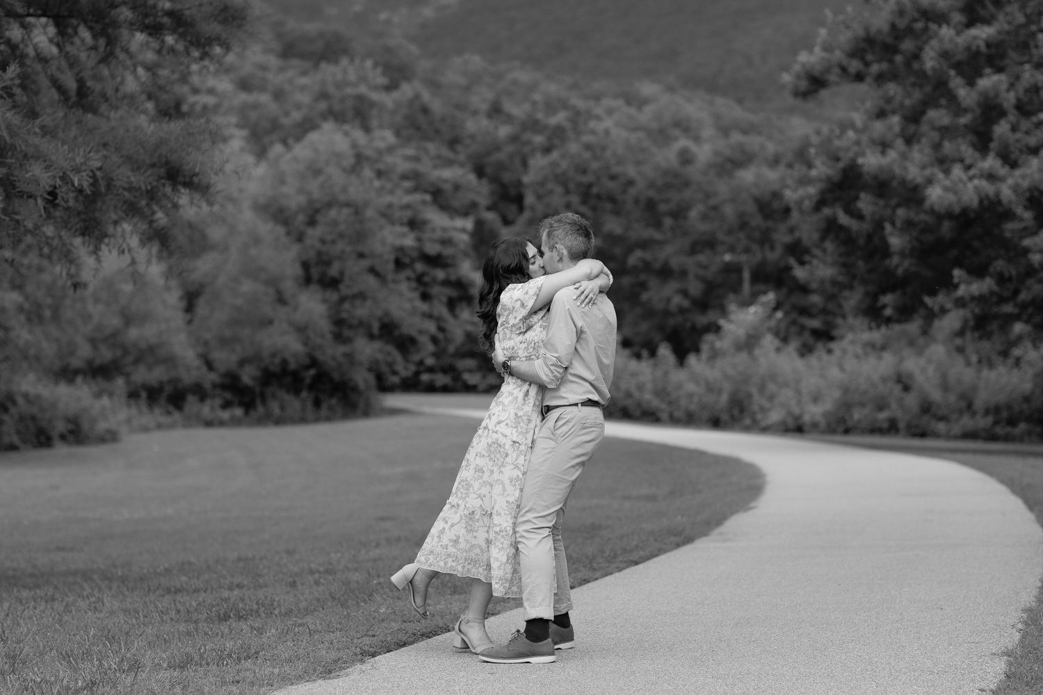 Black and white photo of couple dancing on a winding mountain road.