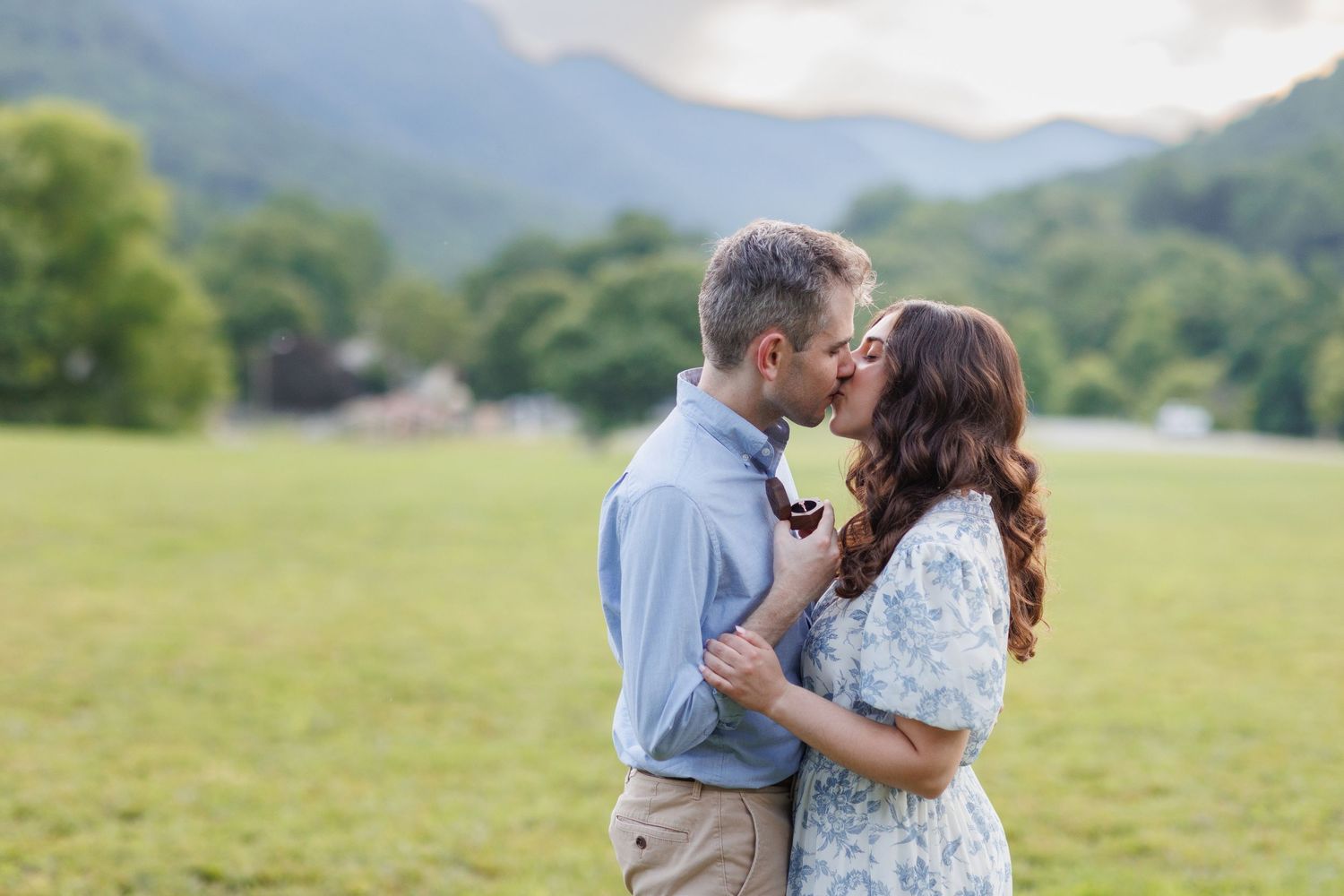 Couple sharing a romantic moment in a mountain meadow during sunset.