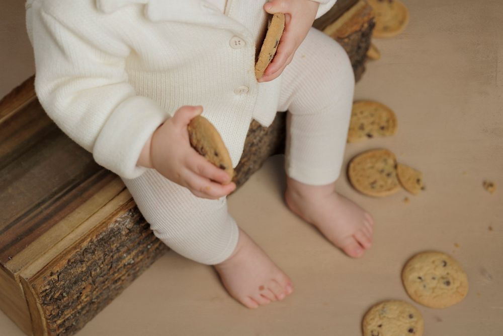 A small hand reaches for freshly baked gingerbread cookies arranged on a wooden surface.