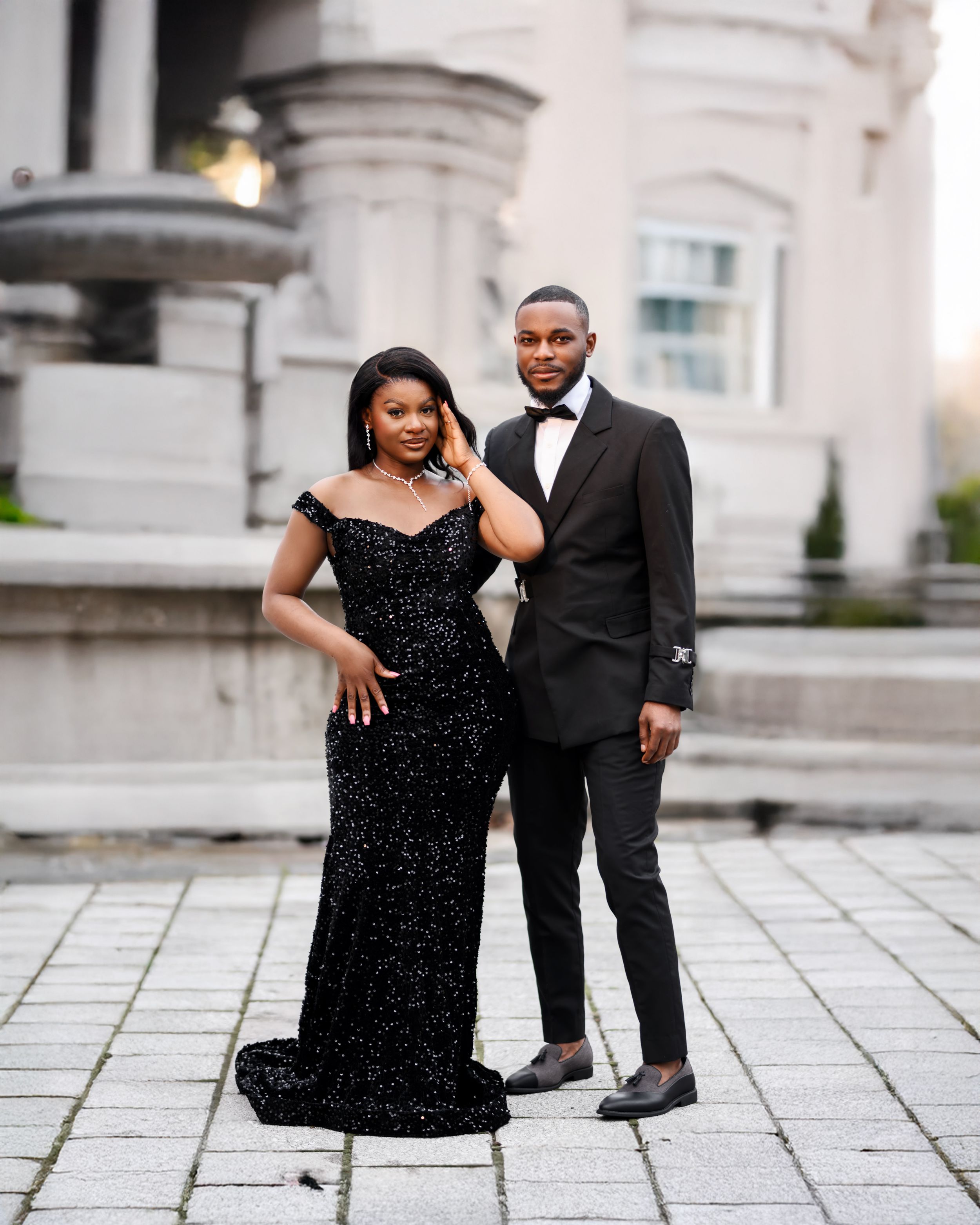 A couple poses together in formal attire and moves across an elegant stone courtyard during a photo session.