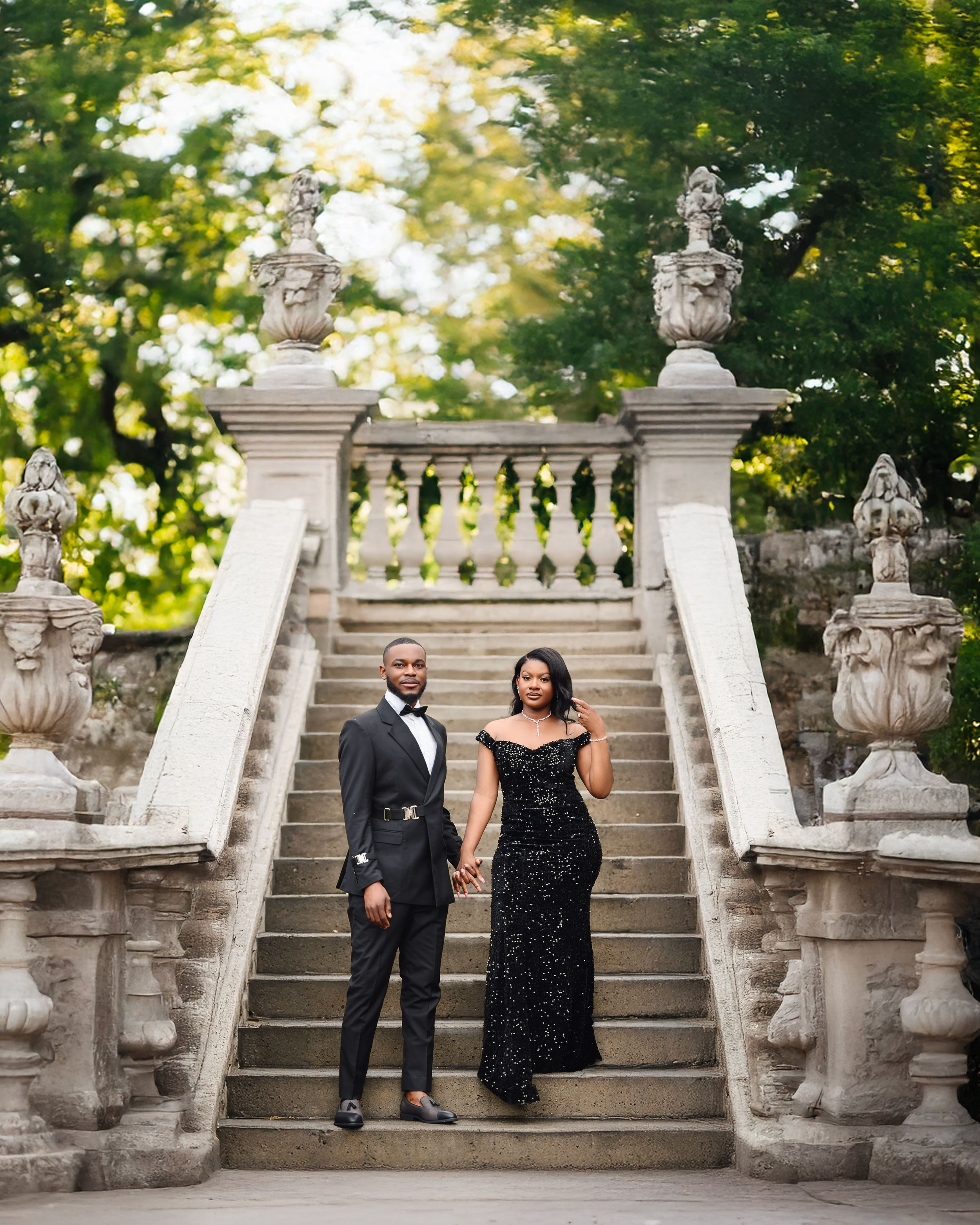 A couple poses elegantly on grand stone stairs adorned with decorative lion statues at a historic venue.