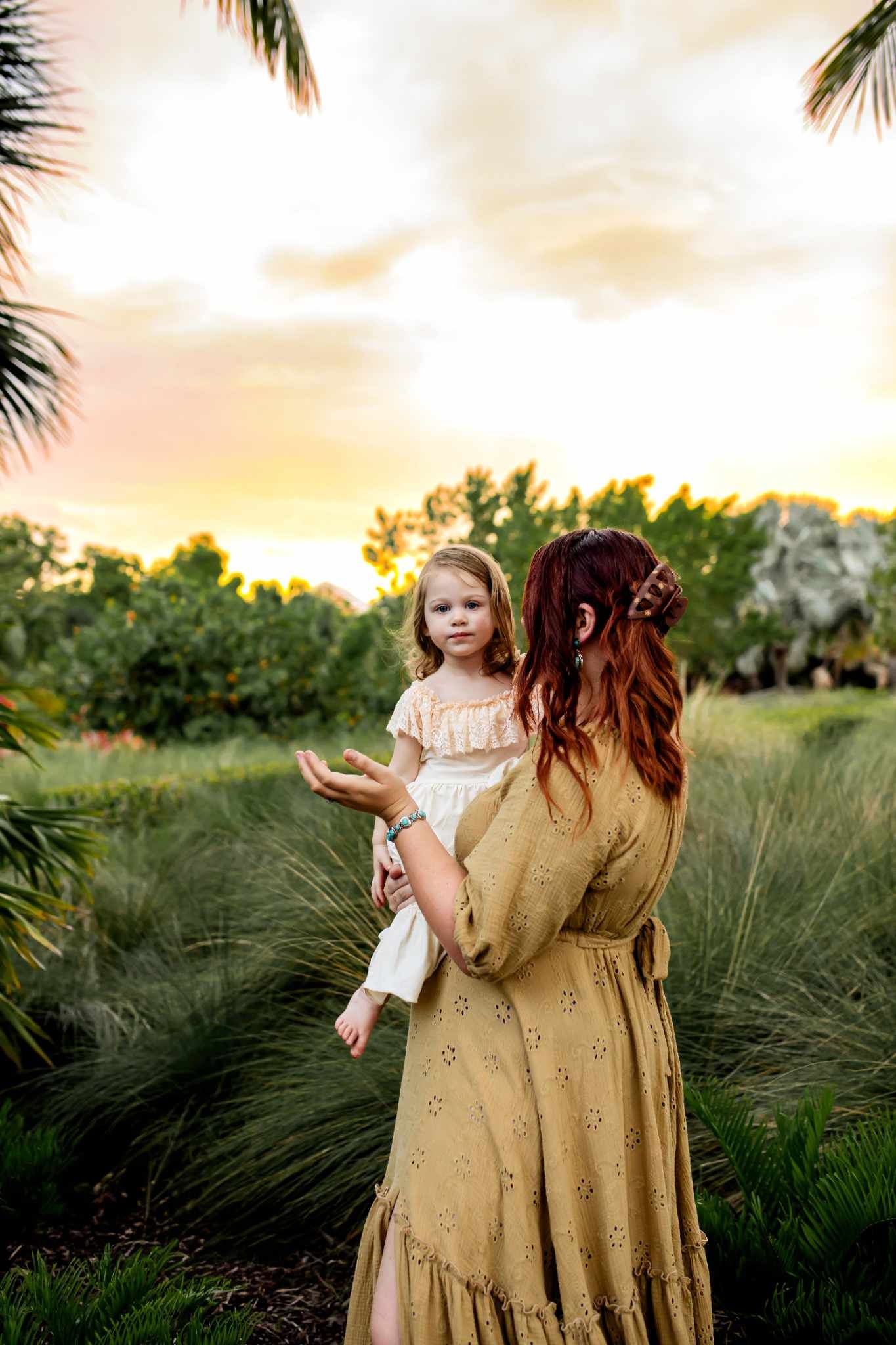 Family portrait session at sunset with palm trees and natural landscaping.
