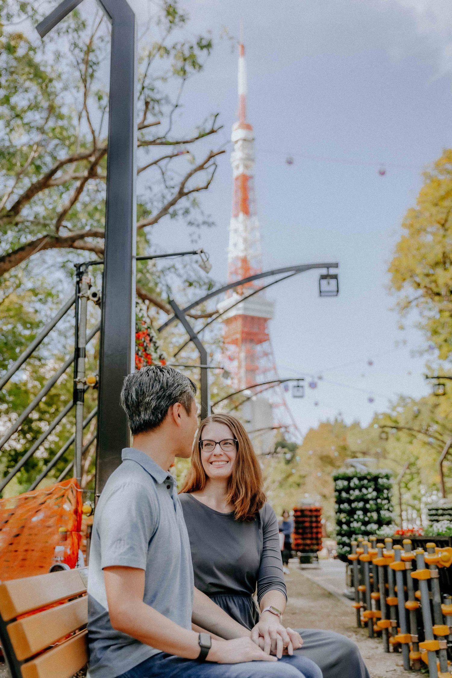 Couple sharing a moment on bench with Tokyo Tower visible in background.