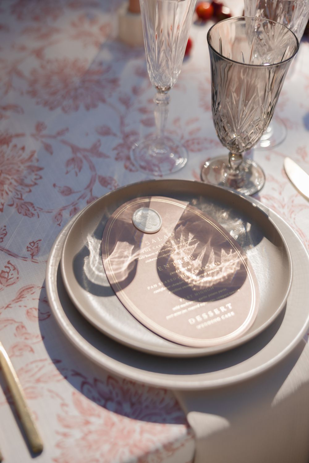 Elegant table setting with crystal glassware casting shadows on white plates with decorative navy blue patterns.