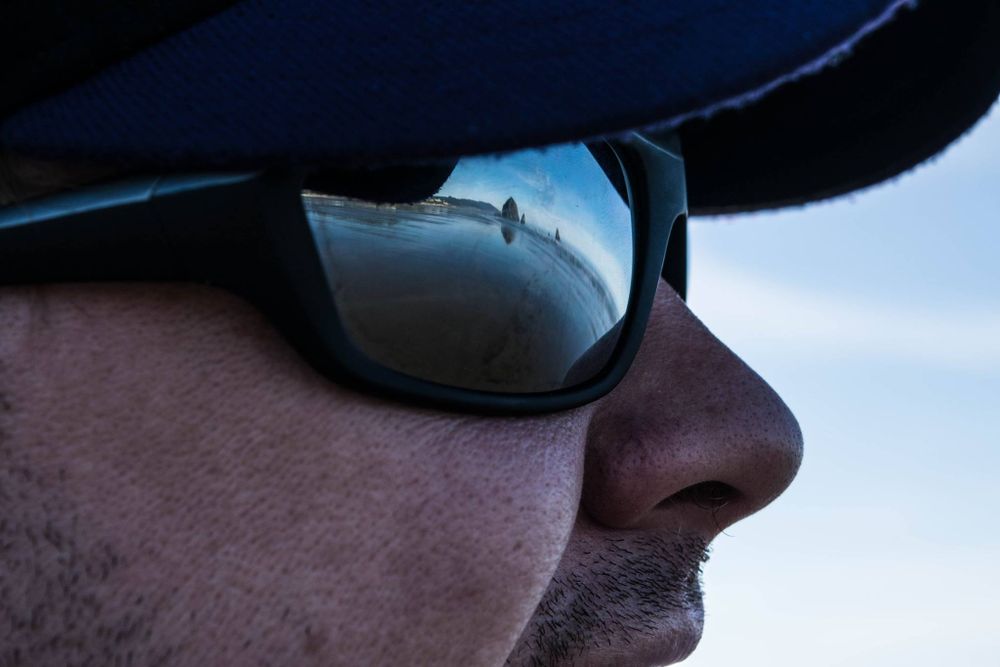 Close-up profile view of sunglasses reflecting a bright sky.