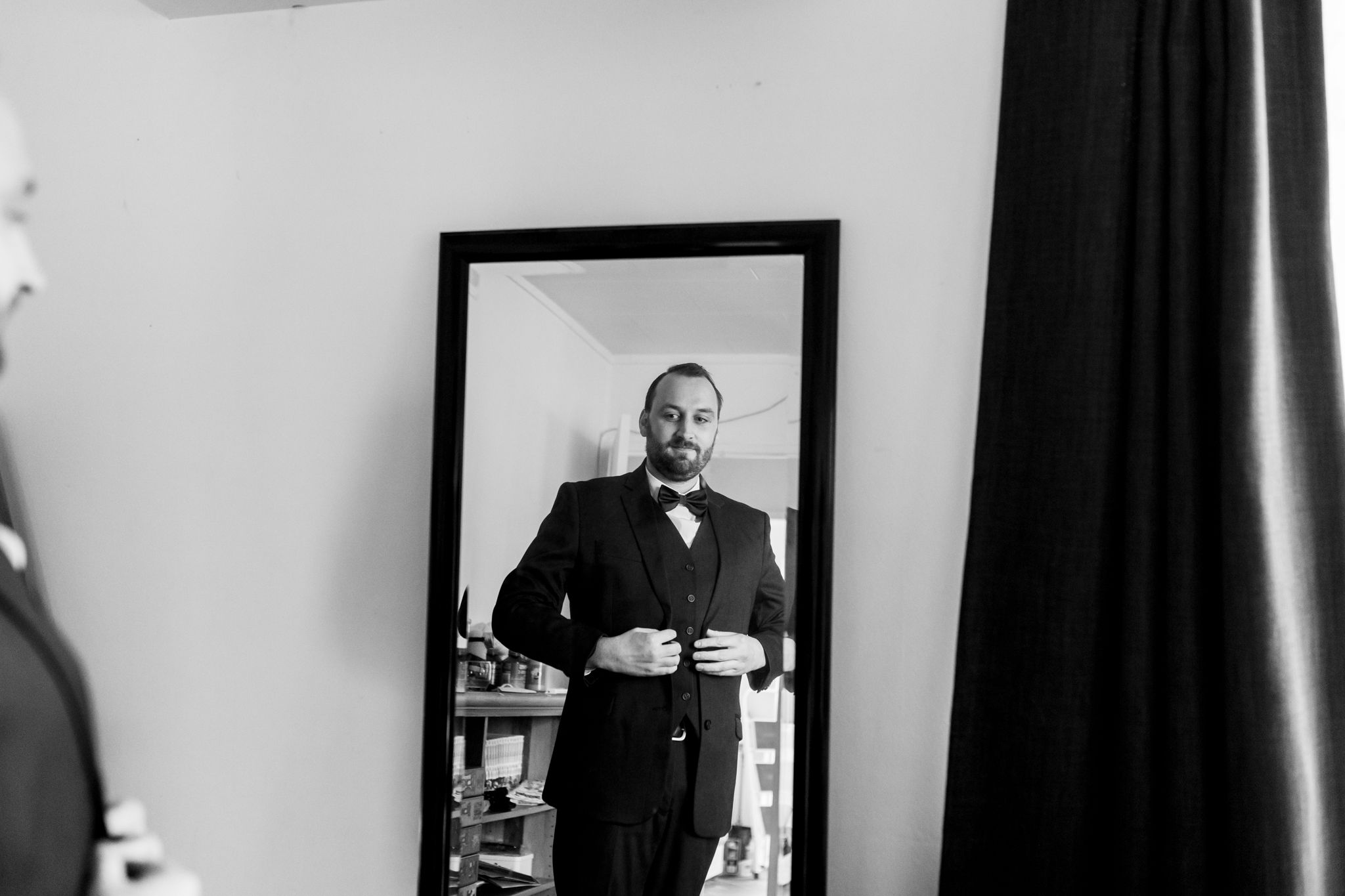 Black and white reflection of formal attire preparation in mirror.