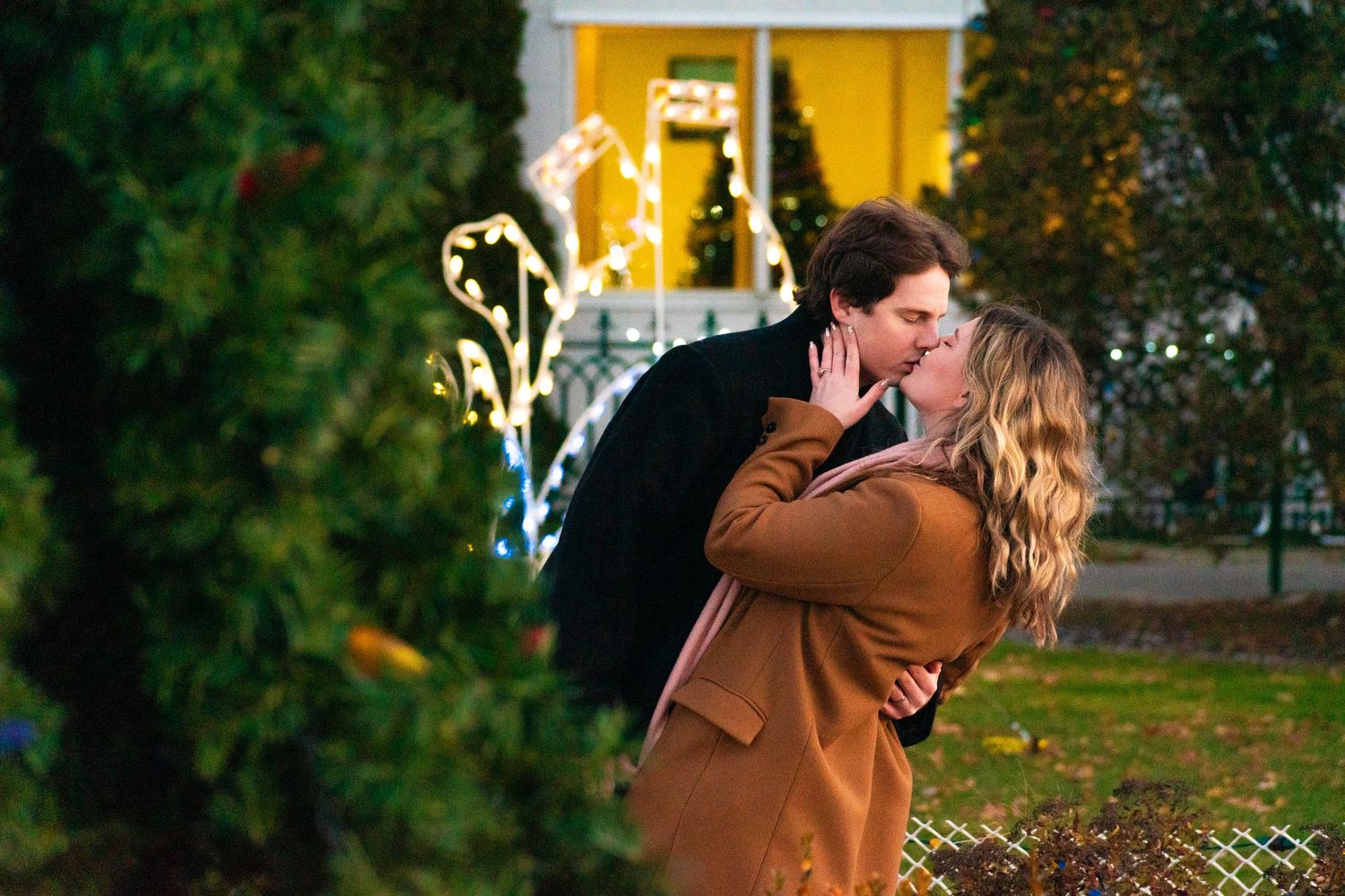 A romantic scene near a yellow building with holiday lights and decorations.