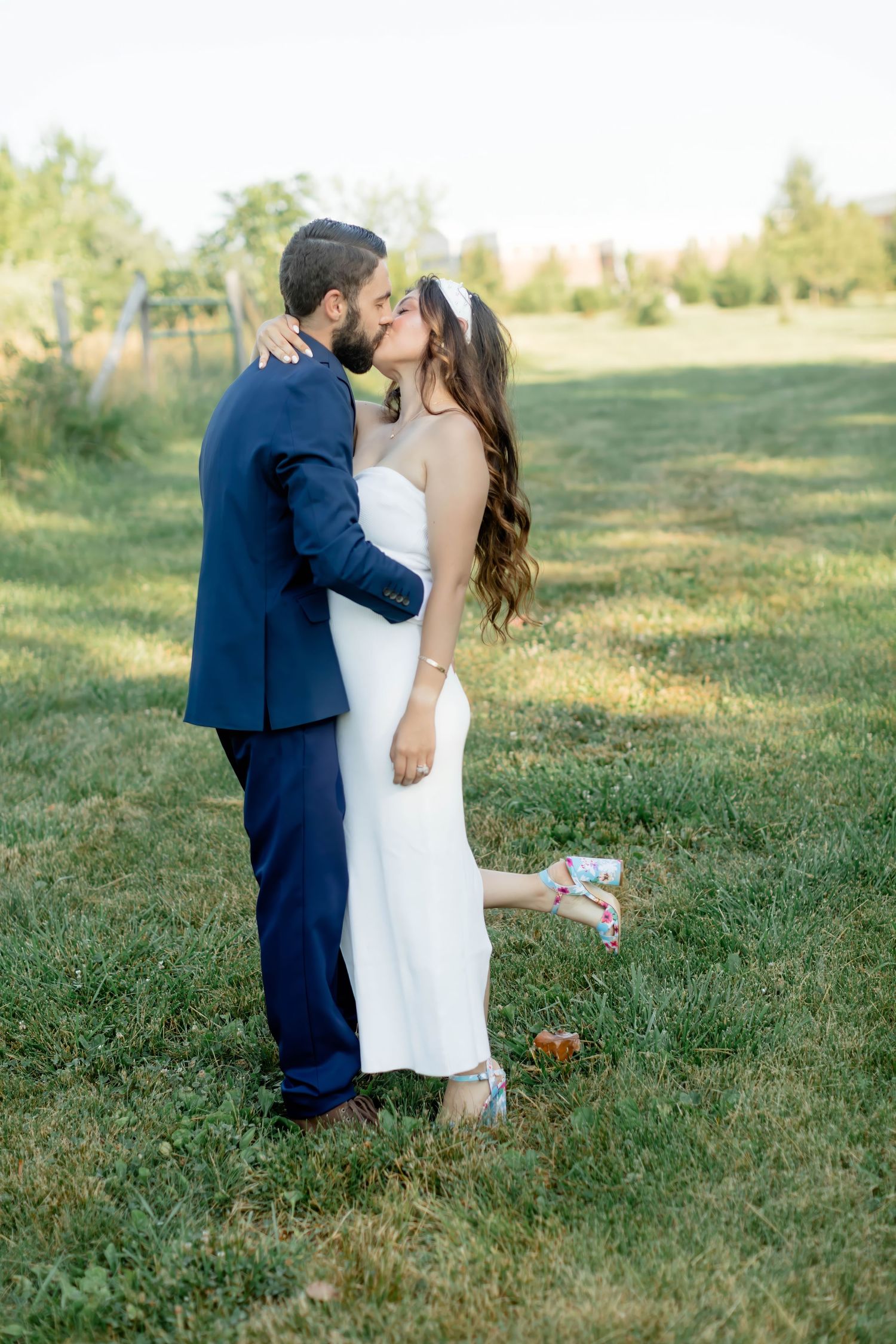 A romantic wedding photo sequence showing a couple sharing a kiss in a sunlit grassy field.