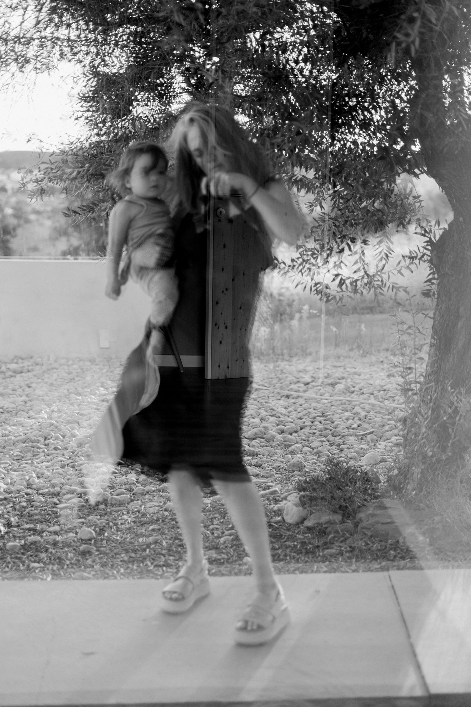Four black and white photos of a young child playing and swinging on an outdoor tree swing.