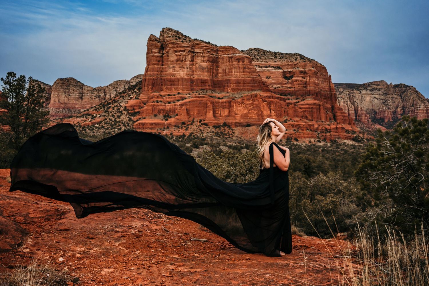 Dramatic black dress photo against red rock formations in desert landscape.