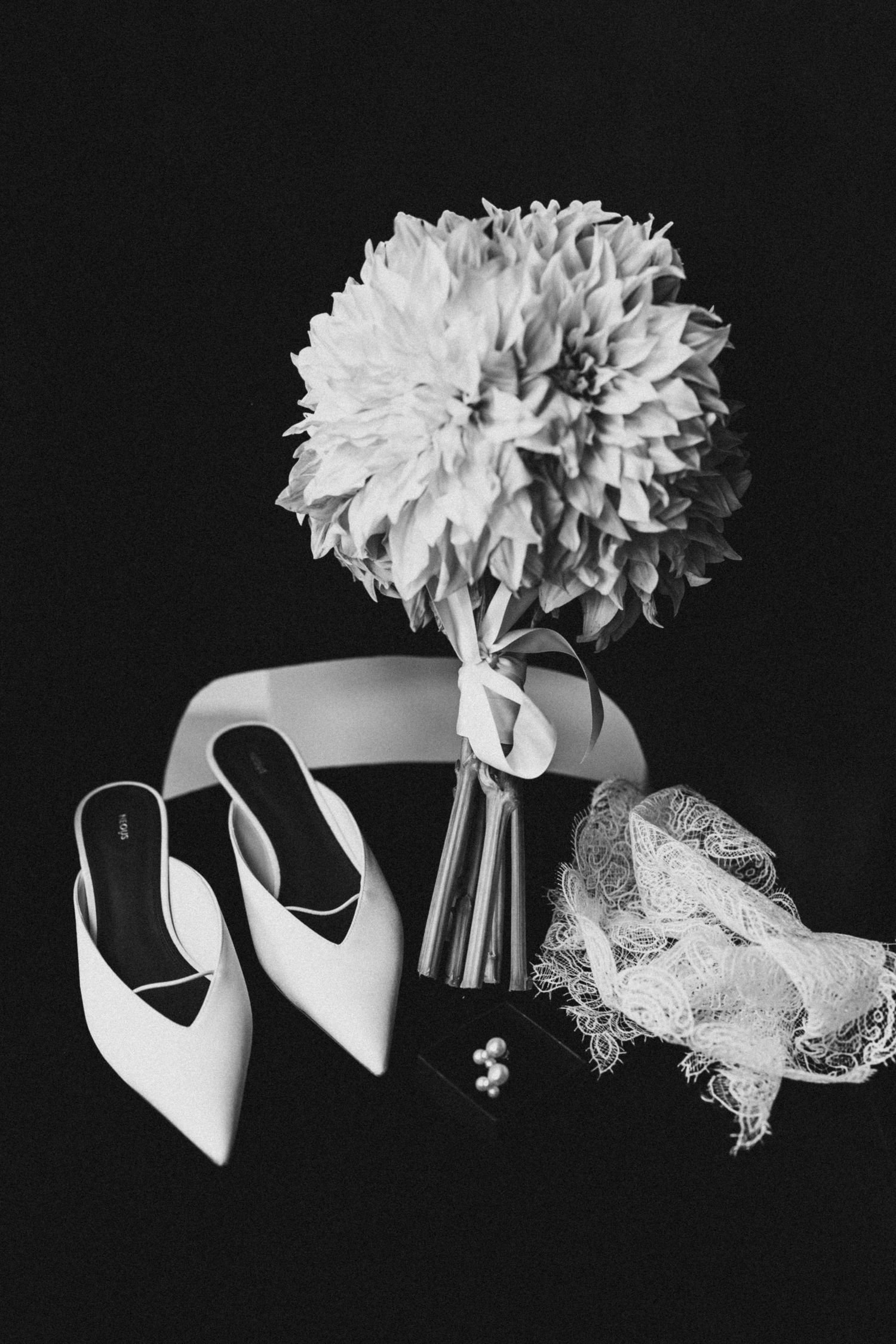 Close-up of white satin ballet pointe shoes tied with ribbons against a black background.