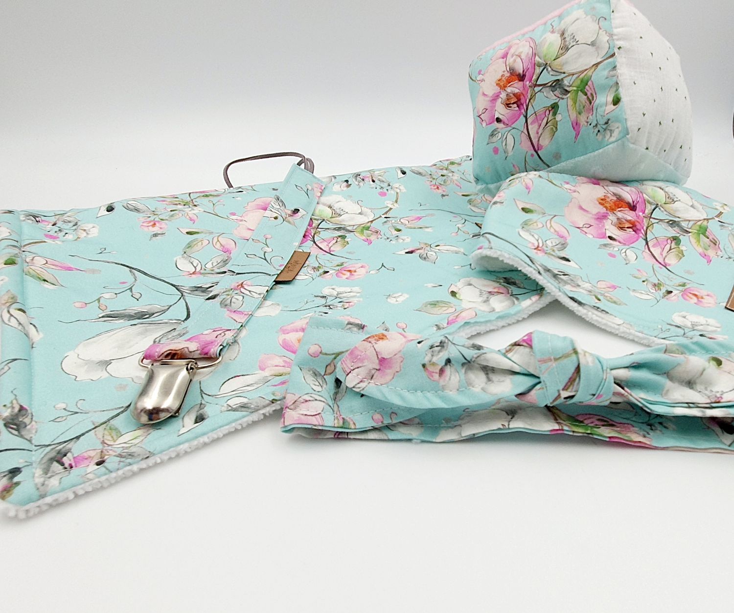 Mint floral baby gift set with swaddle blanket, bow headband, pacifier clip, and cap featuring pink flowers.